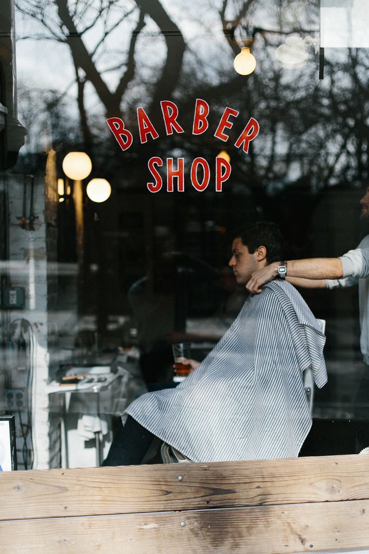 Barbershop storefront view through window with barber working on a client