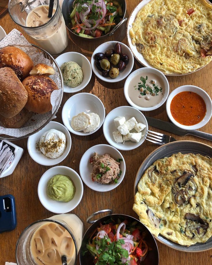 Israeli breakfast spread with shakshuka, dips, bread rolls, and iced coffee from above