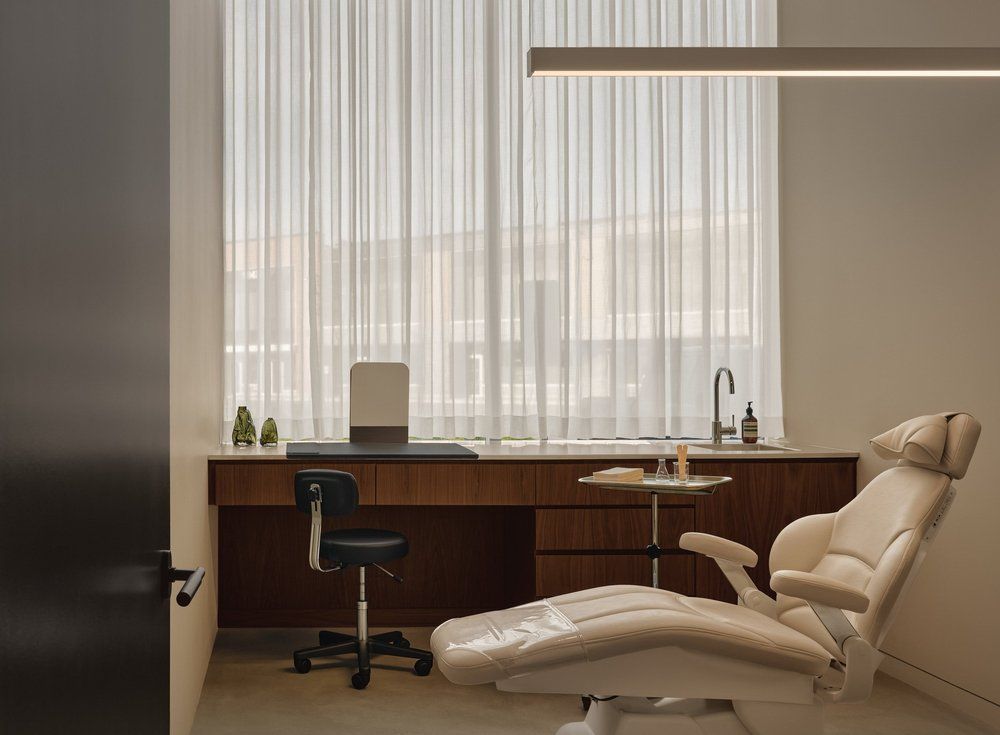 Elegant dental treatment room with cream chair, walnut cabinets and pendant lighting