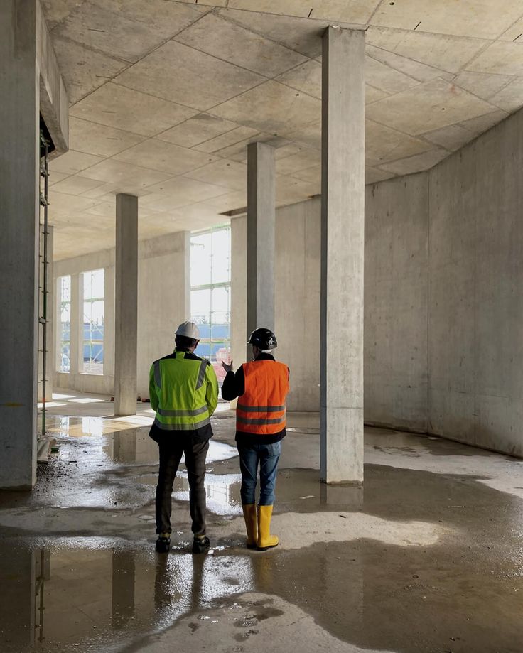 Professional building inspection - two workers in safety vests examining concrete interior