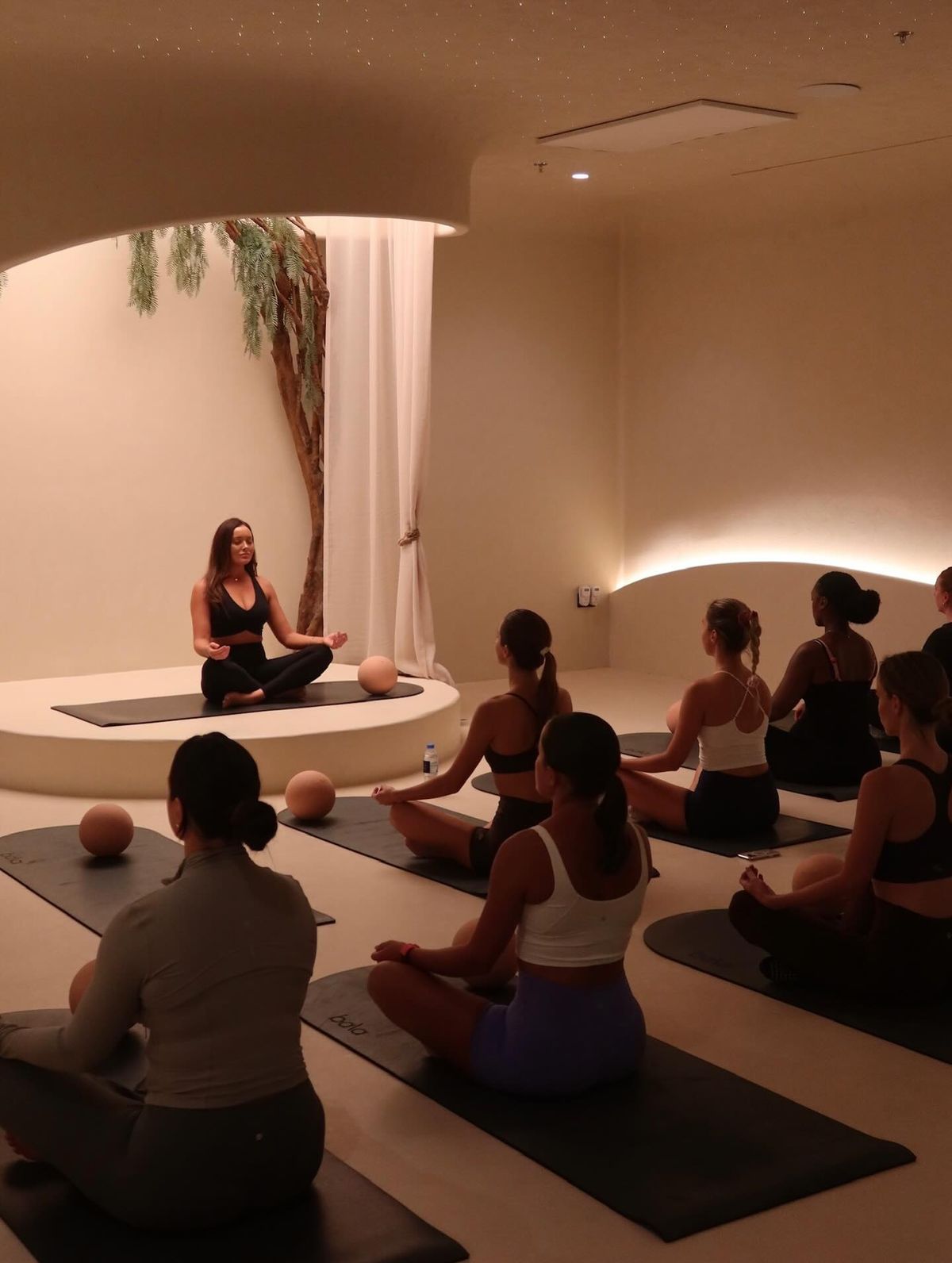 Instructor leading a meditation class in atmospheric studio