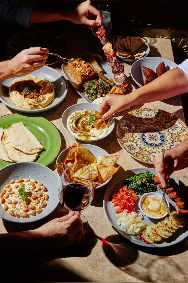 Overhead view of a Mediterranean mezze spread with hummus, tabbouleh, kebabs, and wine