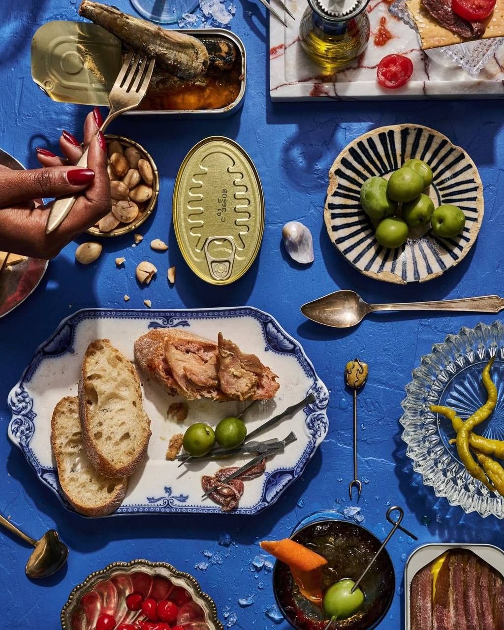Colorful Mediterranean tapas on a vivid blue table with sardines, olives, and bread